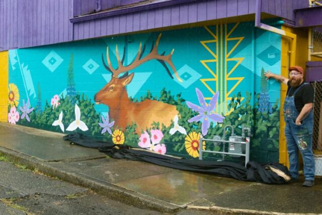 Despite a bout of chilly rains on Saturday morning, a crowd had gathered outside Elks Lodge No. 1943 in Myrtle Creek to get a first glimpse at a new feature for the town, hidden behind a large black sheet. At 10 a.m., it was pulled from the building's exterior to reveal a brand new mural, the first completed in a planned series of upcoming beautifications.

The artwork, made by painters Shane Kelly and Kaley Kelly, is part of an ongoing project by the Myrtle Creek Mural Committee (MCMC) to decorate buildings across the town with original artworks highlighting the town's culture.

According to committee board member Jessica Sharon, the MCMC was formed as a result of last year's Imagine Myrtle Creek meetings, in which citizens expressed a desire to see beautification efforts. For her, the Kelly's mural is an exciting first step.

"We just want to add vibrancy and color to the town, make it more of a destination," Sharon said.

The Kelly's mural is filled with imagery relating to the South County, featuring an elk walking through a patch of wildflowers native to the area. The scene is decorated with a number of symbols and patterns used in the basketry of local tribes.

"They city's slogan and out theme is 'where nature is your neighbor,' so we really wanted to encompass the local wildlife and flora of this area," Painter and MCMC president Shane Kelly said. "I love Myrtle Creek and I love Douglas County, so I'm just excited to bring some art to town."

For More Information Please Visit www.nrtoday.com